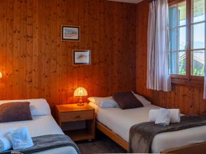 two beds in a room with wooden walls at Chalet Mustela by Interhome in Nendaz