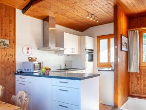 cocina con armarios blancos y techo de madera en Chalet Mustela by Interhome, en Nendaz