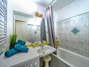 a bathroom with a sink and a tub and a mirror at Studio Soyouz Vanguard-63 by Interhome in Le Corbier