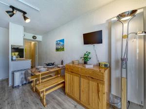 a kitchen with a table and a tv on a wall at Studio Soyouz Vanguard-63 by Interhome in Le Corbier