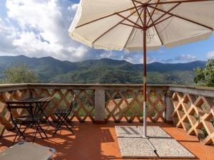 patio con mesa y sombrilla en el balcón en Apartment Canneto-1 by Interhome, en Stellanello