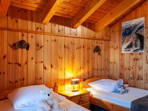 two teddy bears sitting on two beds in a wooden room at Chalet Valet de Coeur by Interhome in Nendaz