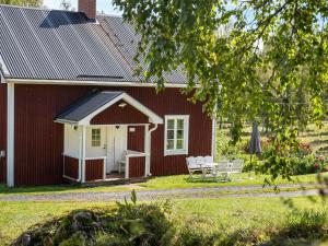 ein rotes Haus mit zwei Stühlen und einem Tisch davor in der Unterkunft Chalet Långban by Interhome in Filipstad