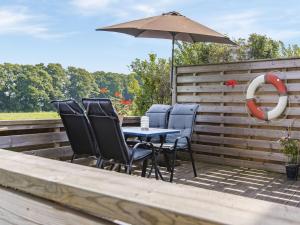 een patio met een tafel en stoelen en een parasol bij Holiday Home Täppan - SKO184 by Interhome in Bromölla