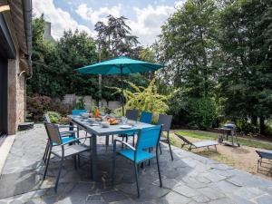 einen Tisch und Stühle mit Sonnenschirm auf einer Terrasse in der Unterkunft Villa La Boissière - MLX200 by Interhome in Morlaix