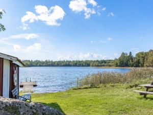 een uitzicht op een meer met een gebouw en een picknicktafel bij Holiday Home Bredasjö by Interhome in Gnitteryd
