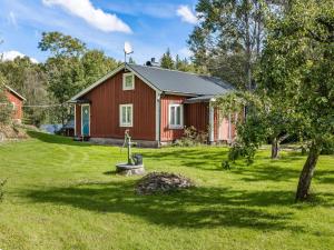 a red house in a yard with a tree and grass at Holiday Home Bredasjö - B in Gnitteryd