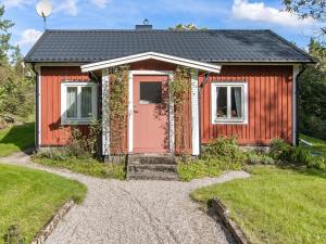 a red house with a pink door on a gravel driveway at Holiday Home Bredasjö - B in Gnitteryd