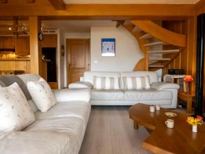 una sala de estar con 2 sofás blancos y una mesa de madera. en Apartment Licorne by Interhome, en Verbier