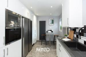 a kitchen with white cabinets and a black refrigerator at Bright and Warm 3-bed Home in Nottingham by Renzo, Free Driveway Parking, Close to Wollaton Park! in Nottingham