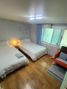 a bedroom with two beds and a chair and a window at Appletree Guesthouse in Seoul