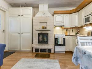 a kitchen with white cabinets and a fireplace at Holiday Home Rajala by Interhome in Neuvosenniemi