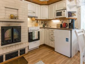 eine Küche mit weißen Geräten und einem Kamin in der Unterkunft Holiday Home Rajala by Interhome in Neuvosenniemi
