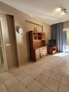 a living room with a tv and a tiled floor at Limnaria Gardens Paphos, near beach in Paphos