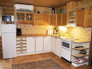 a kitchen with white appliances and wooden cabinets at Holiday Home Metsälä by Interhome in Kolinkylä