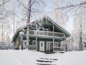 a green house in the snow with trees at Holiday Home Kesäranta by Interhome in Simanala