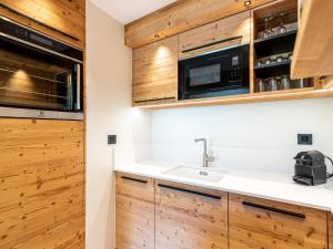 a kitchen with wooden cabinets and a sink at Apartment Les Cimes - Le Lac by Interhome in Tignes
