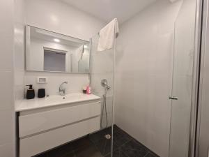 een witte badkamer met een wastafel en een douche bij Herzliya Marina - By Beach Apartments TLV in Herzliyya B