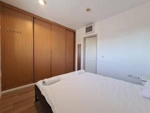 een slaapkamer met een wit bed en houten kasten bij Herzliya Marina - By Beach Apartments TLV in Herzliyya B