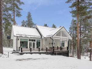 a white house with a porch in the snow at Holiday Home Teppolan rinne by Interhome in Salla