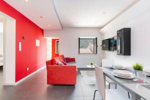 uma sala de estar com uma parede de acento vermelho e uma cadeira vermelha em Casa dos Mouros - 2 Quartos e Cozinha - Serra da Estrela - Loriga em Longa