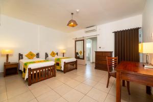 博瓦隆的住宿－熱帶的嚮往公寓式酒店，一间卧室配有两张床、一张桌子和一张书桌