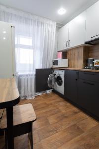 uma cozinha com armários brancos e uma máquina de lavar e secar roupa em Majestic em Petropavl