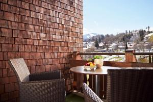 einen Tisch und Stühle auf einem Balkon mit einer Obstschale in der Unterkunft Lindner Hotel Oberstaufen Parkhotel, part of JdV by Hyatt in Oberstaufen