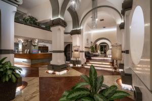 a lobby with columns and plants in a building at Hotel Croce Di Malta in Florence