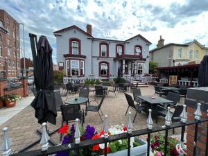 a patio with tables and chairs in front of a building at Southport Metro Hotel in Southport