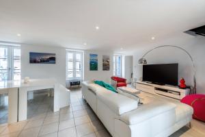 a living room with a white couch and a tv at Villa Sur le Port in Roscoff
