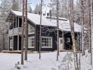 a black house in the woods in the snow at Holiday Home Levin ahmahovi 2b by Interhome in Sirkka