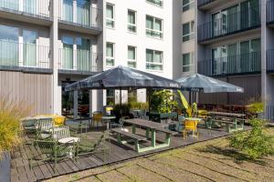 un patio avec des tables, des chaises et des parasols en face d'un bâtiment dans l'établissement Residence Inn by Marriott Brussels Airport, à Diegem