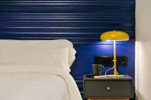 a bedroom with a bed and a yellow lamp on a night stand at Arte Suites by Olala Homes in Hospitalet de Llobregat