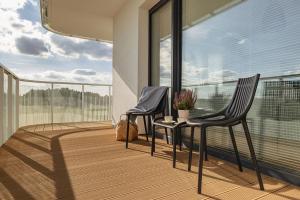 two chairs sitting next to a table on a balcony at Family Apartment with Gym and Swimming Pool by Renters Prestige in Kołobrzeg
