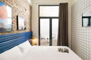 a bedroom with a white bed and a brick wall at Arte Suites by Olala Homes in Hospitalet de Llobregat
