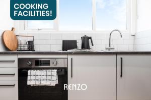 a kitchen with white cabinets and a black oven at Cosy Studio Apartment in Derby by Renzo, Brilliant Location, Close to Derby City Centre in Derby