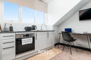a kitchen with white cabinets and a table and a chair at Cosy Studio Apartment in Derby by Renzo, Brilliant Location, Close to Derby City Centre in Derby