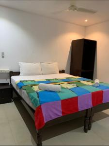 a bed in a room with a colorful blanket on it at Palolem Cottages in Palolem