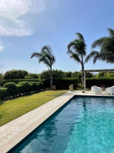 una piscina in un cortile con palme di B&B Sun Of Sicily a Noto