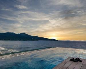 a swimming pool with a view of the ocean at sunset at Alacarte Luxury Ocean View Condotel in Da Nang