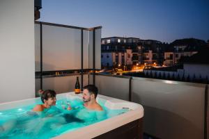 2 personnes dans une baignoire sur un balcon dans l'établissement Onyx Luxury, à Sárvár