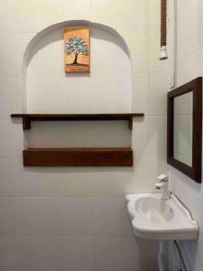 La salle de bains est pourvue d'un lavabo et d'une photo d'un arbre. dans l'établissement Bhome Zanzibar, à Kiwengwa
