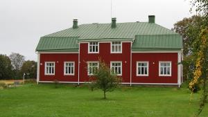 a red barn with a green roof on a grass field at Övermark Bed & Breakfast in Ylimarkku