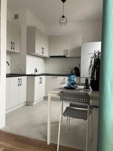 a kitchen with white cabinets and a table and chairs at Apartament Zielony in Łódź