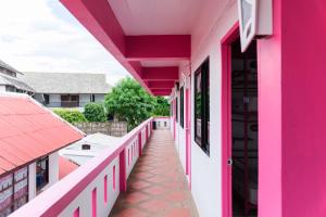 a pink house with a hallway leading to a balcony at Slumber Party Chiang Mai in Chiang Mai