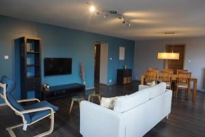 a living room with a white couch and a dining room at L'Aubach - appartement spacieux in Scherwiller