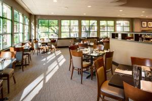 un comedor con mesas, sillas y ventanas en Sheraton San Jose, en Milpitas