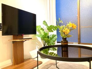 un soggiorno con TV e tavolo con fiori di Roppongi Place a Tokyo