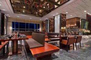 um restaurante com mesas e cadeiras e um bar em Sheraton Qingdao Licang Hotel em Qingdao